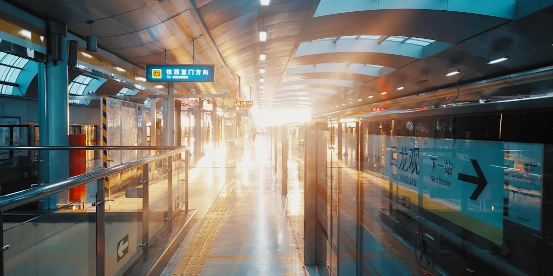 An empty Beijing subway platform at sunrise with Chinese station signage and a train pulling in.