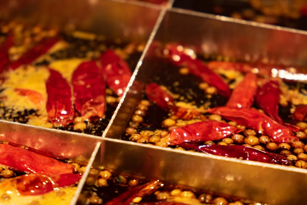 A Sichuan hot pot table with red broth, side dishes, and a communal dining setup.