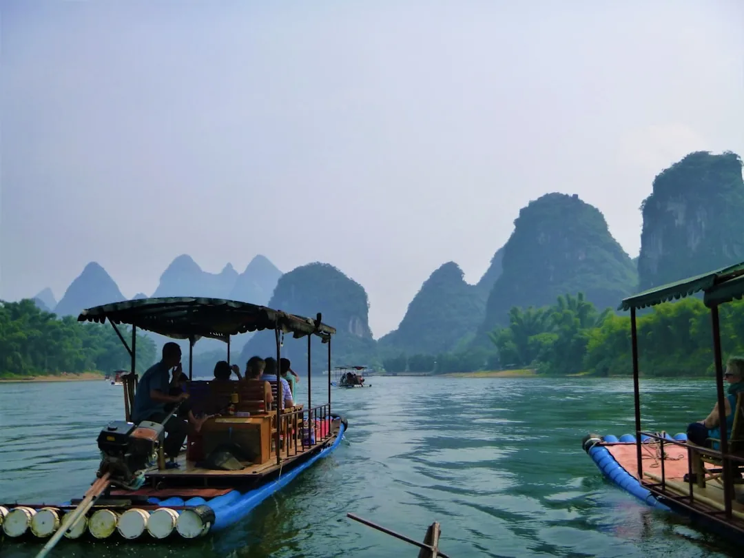 Karst mountains along the Li River near Guilin with boats on calm water.