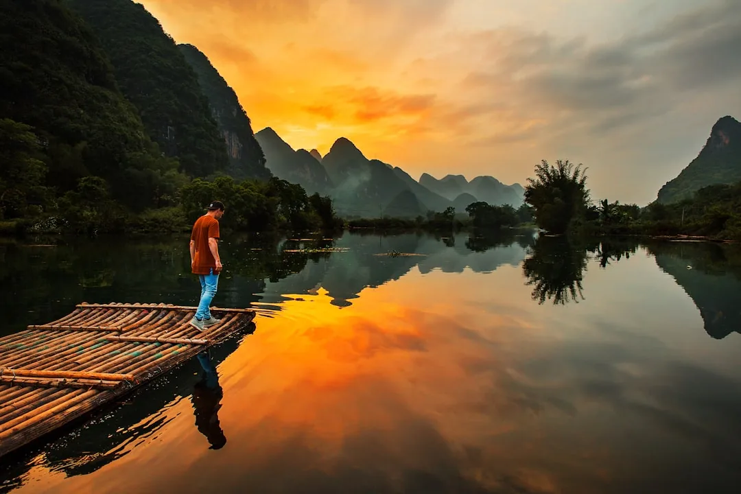 A bamboo raft on the Li River near Yangshuo at sunset between dark karst hills.