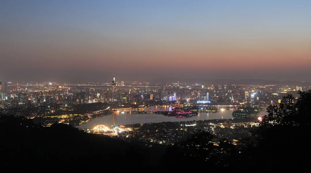Nanjing skyline illuminated at dusk with distant mountains behind the city.