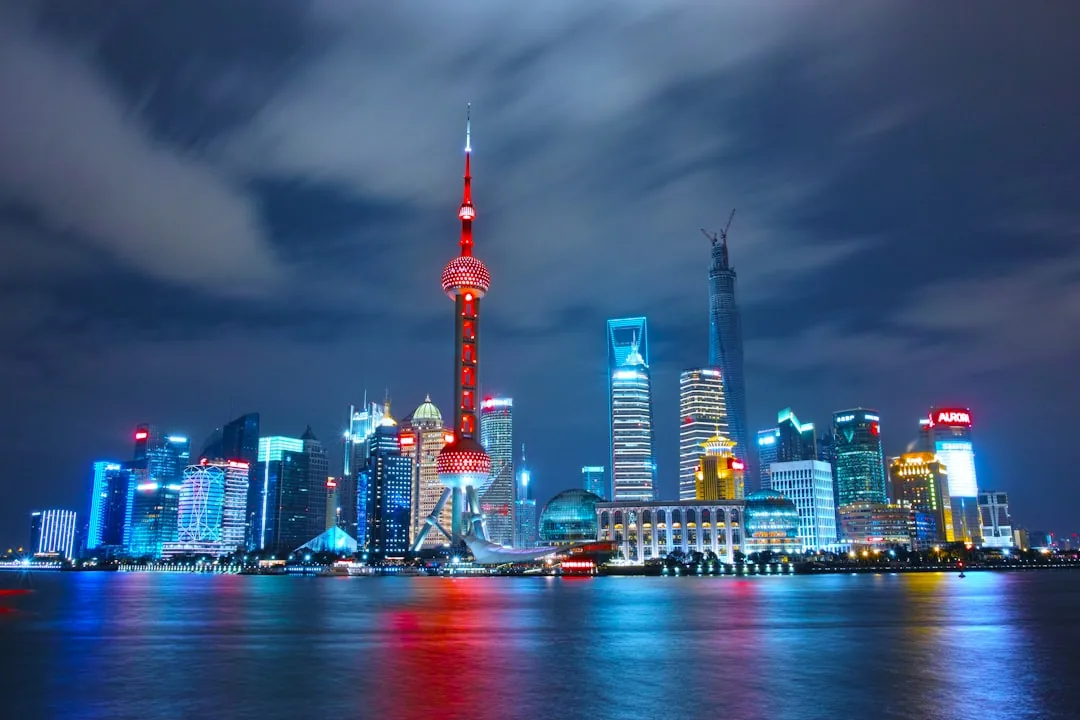 The Bund skyline at night in Shanghai with the Huangpu River reflecting the city lights.