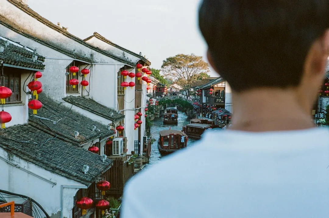 A Suzhou old-town canal with boats, red lanterns, and waterside buildings.
