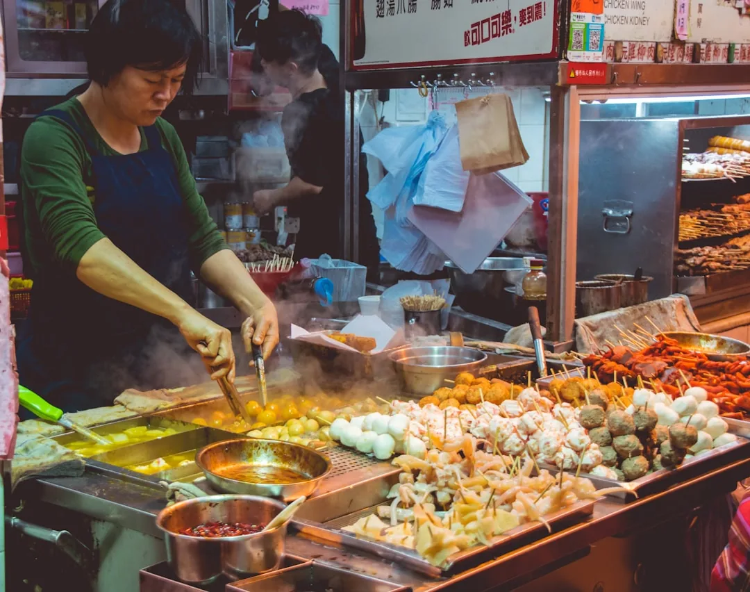 A busy Xi'an Muslim Quarter food street with vendors preparing snacks for visitors.