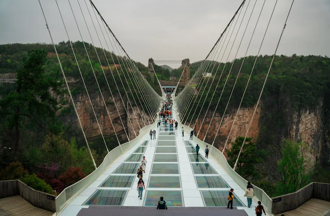 Visitors walking across a glass bridge above the canyon scenery in Zhangjiajie.